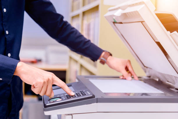 istock Close-up business man Hand press button on panel of printer, printer scanner laser office copy machine supplies start concept. 1004838646