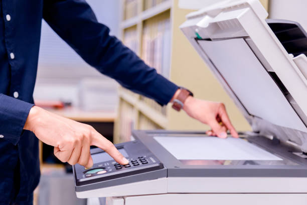 istock Close-up business man Hand press button on panel of printer, printer scanner laser office copy machine supplies start concept. 1004838676