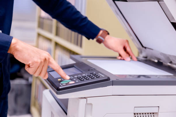 istock Close-up business man Hand press button on panel of printer, printer scanner laser office copy machine supplies start concept. 1004838706