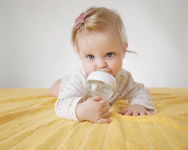 istock Cute baby with bottle on bed 1004838920