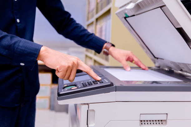 istock Close-up business man Hand press button on panel of printer, printer scanner laser office copy machine supplies start concept. 1004838996