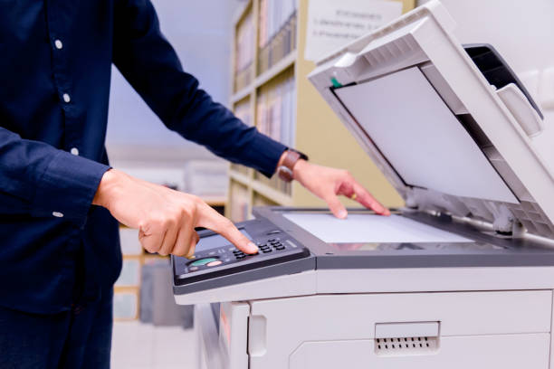 istock Close-up business man Hand press button on panel of printer, printer scanner laser office copy machine supplies start concept. 1004839060