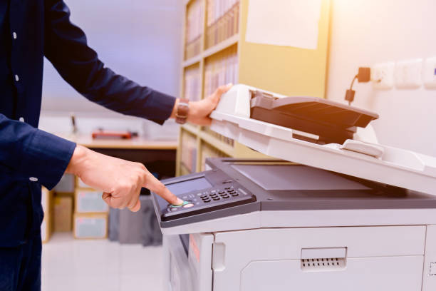 istock Close-up business man Hand press button on panel of printer, printer scanner laser office copy machine supplies start concept. 1004839330