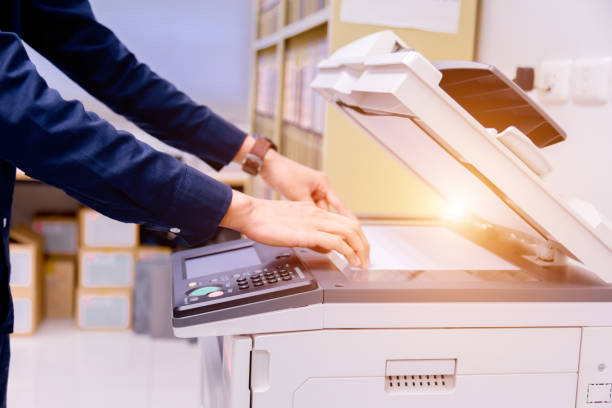istock Close-up business man Hand press button on panel of printer, printer scanner laser office copy machine supplies start concept. 1004839410