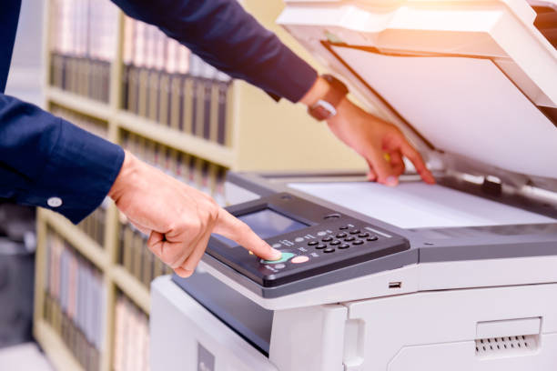 istock Close-up business man Hand press button on panel of printer, printer scanner laser office copy machine supplies start concept. 1004839732