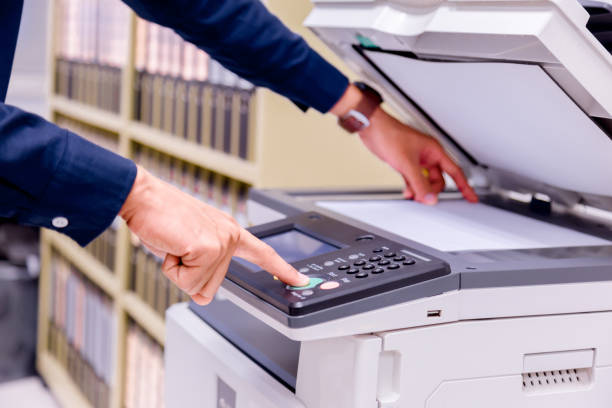istock Close-up business man Hand press button on panel of printer, printer scanner laser office copy machine supplies start concept. 1004839756