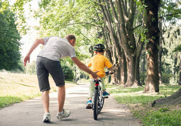istock Father learn his little son to ride a bicycle 1004842750