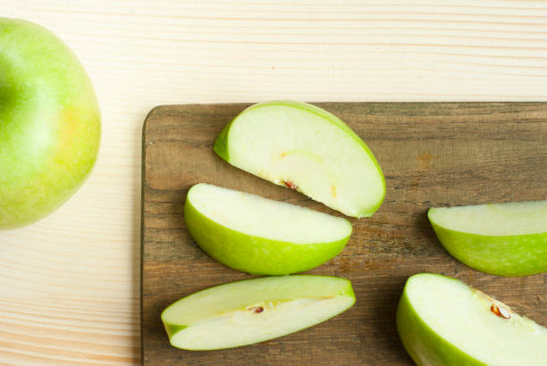 Green apples sliced green apple on wooden cutting board green apple slice overhead stock pictures, royalty-free photos & images
