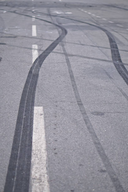 résumé des roues pneu noir provoquée par la voiture de drift sur la route. freinage à un passage pour piétons et une route avec des marques. photo en stock pour la conception - tire track pattern black and white braking photos et images de collection