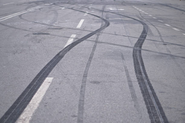 zusammenfassung des schwarzen reifen räder verursacht durch drift auto auf der straße. bremsen an einem fußgängerüberweg und eine straße mit markierungen. standardbild für design - tire track track asphalt skidding stock-fotos und bilder