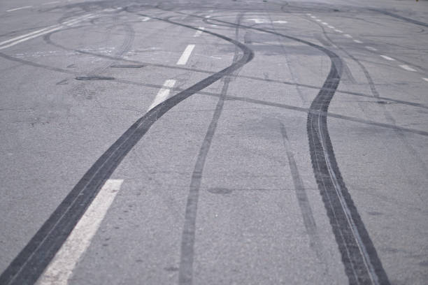 abstract di ruote pneumatiche nere causate dall'auto drift sulla strada. frenata ad un attraversamento pedonale e a una strada con marcature. foto d'archivio per il design - sbandare foto e immagini stock