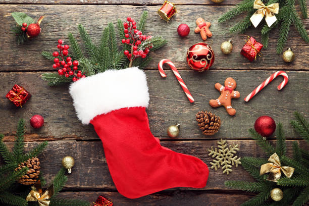 istock Red stocking with fir-tree branches and christmas decorations on wooden table 1004868902