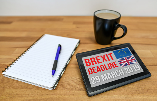 Tablet device on a table with a notebook and coffee mug. The Brexit deadline is 29th March 2019 when the UK leaves the EU.