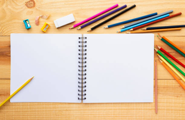istock Many colored pencils with the white notebook on wood table for painting. Copy space for your text. 1004877674