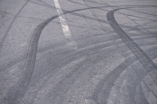 résumé des roues pneu noir provoquée par la voiture de drift sur la route. freinage à un passage pour piétons et une route avec des marques. photo en stock pour la conception - tire track pattern black and white braking photos et images de collection