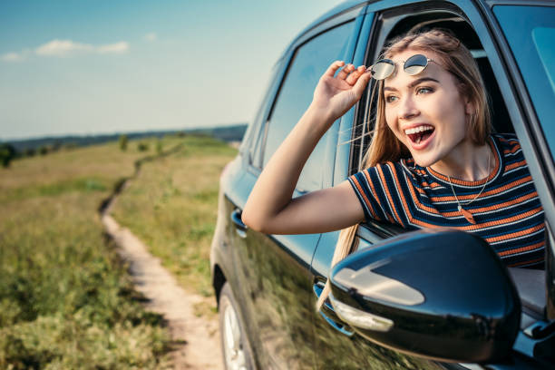 istock happy surprised woman leaning out from car window 1004889876