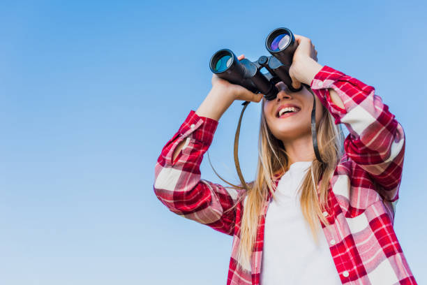 istock low angle view of female traveler looking through binoculars against blue sky 1004891500