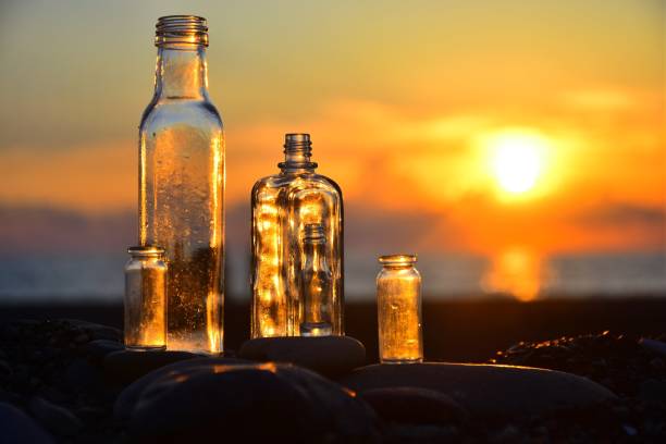 istock Close-Up Of Empty Bottles On Table Against Orange Sky 1004894454