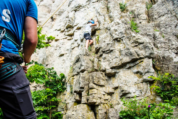 istock A rock climbing instructor belaying a 12 year-old boy on a rock face 1004897780