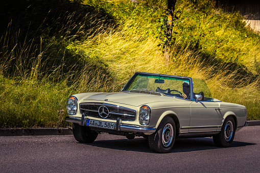 A procession of vintage automobiles gracefully cruises along a tranquil country road on the enchanting Samsø Island in Denmark. The photo was taken at Præstegården  street in Nordby, Denmark on September 9th 2023.