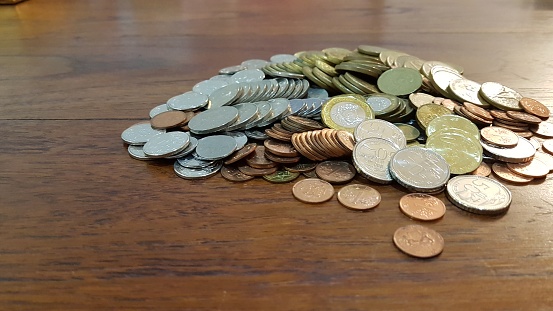 Heap of various coins on wooden table top - conceptual image of collecting coins for saving