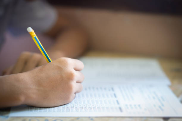 istock Student holding pencil writing answer of question on paper test examination 1004923488