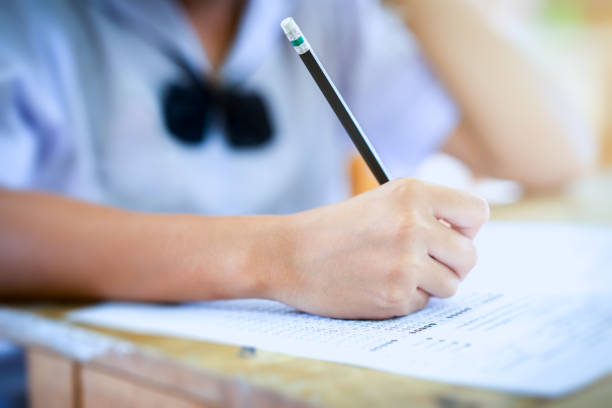 istock Student holding pencil writing answer of question on paper test examination 1004923494