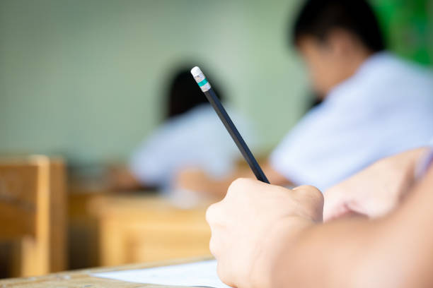 istock Student holding pencil writing answer of question on paper test examination 1004923594