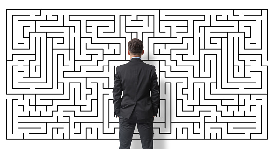 Businessman looking at a labyrinth on a white wall