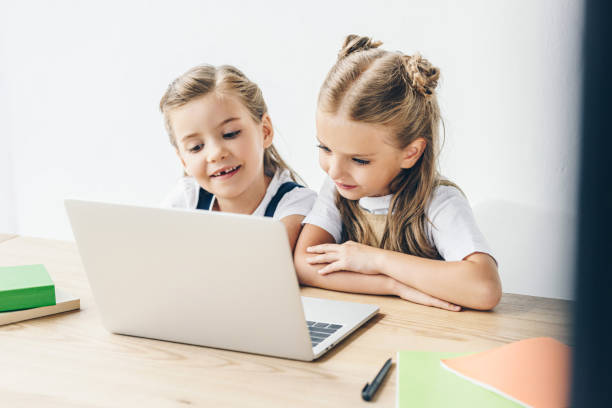 istock happy little schoolgirls using laptop for studying isolated on white 1004936740