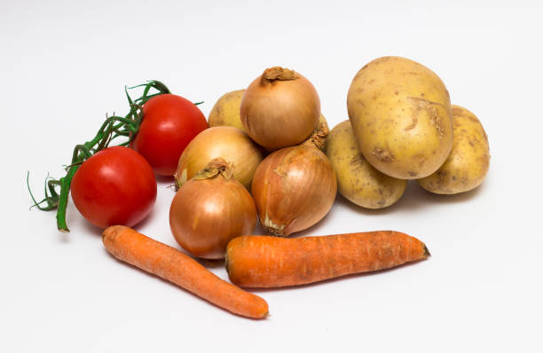 istock onions, potatoes, tomatoes, carrots on a white background. 1004943306