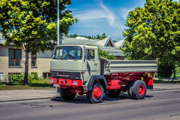 A red truck with a black steering wheel. The truck is parked in a lot