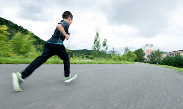 istock Little boy running in the park footpath 1004948740