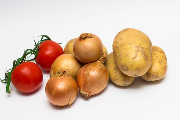 istock onions, potatoes, tomatoes, on white background. 1004976370