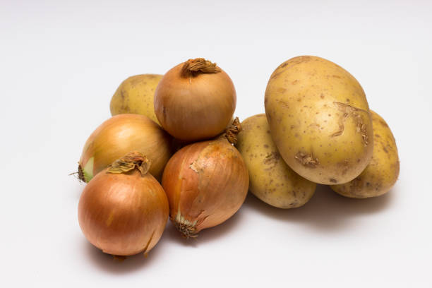 istock onions and potatoes on a white background. 1004976496