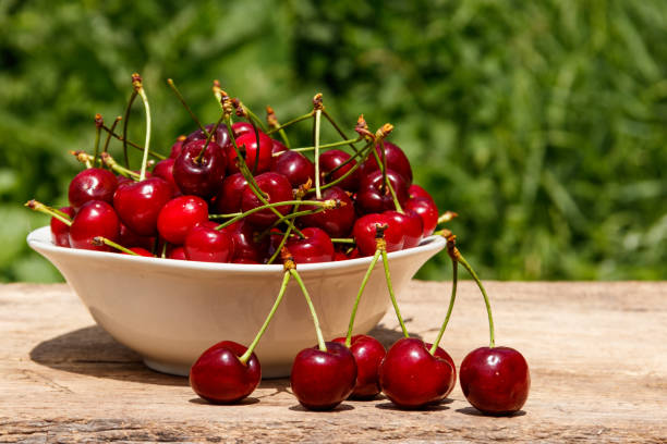 istock Bowl with fresh cherry on rustic wooden table outdoor 1004987394