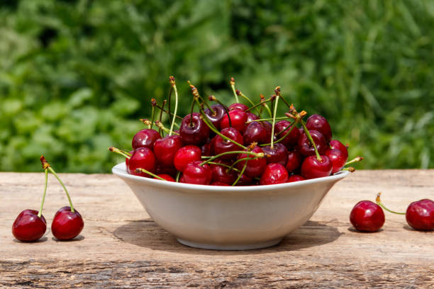 istock Bowl with fresh cherry on rustic wooden table outdoor 1004987398