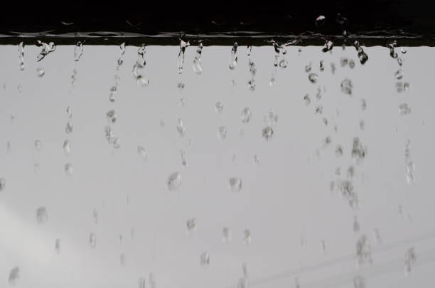 Rain drops fall from the roof end (eave) with natural clear background.