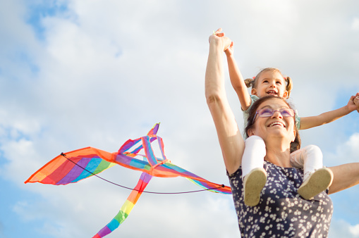 Grandmother and granddaughter having fun, playing with kite together.