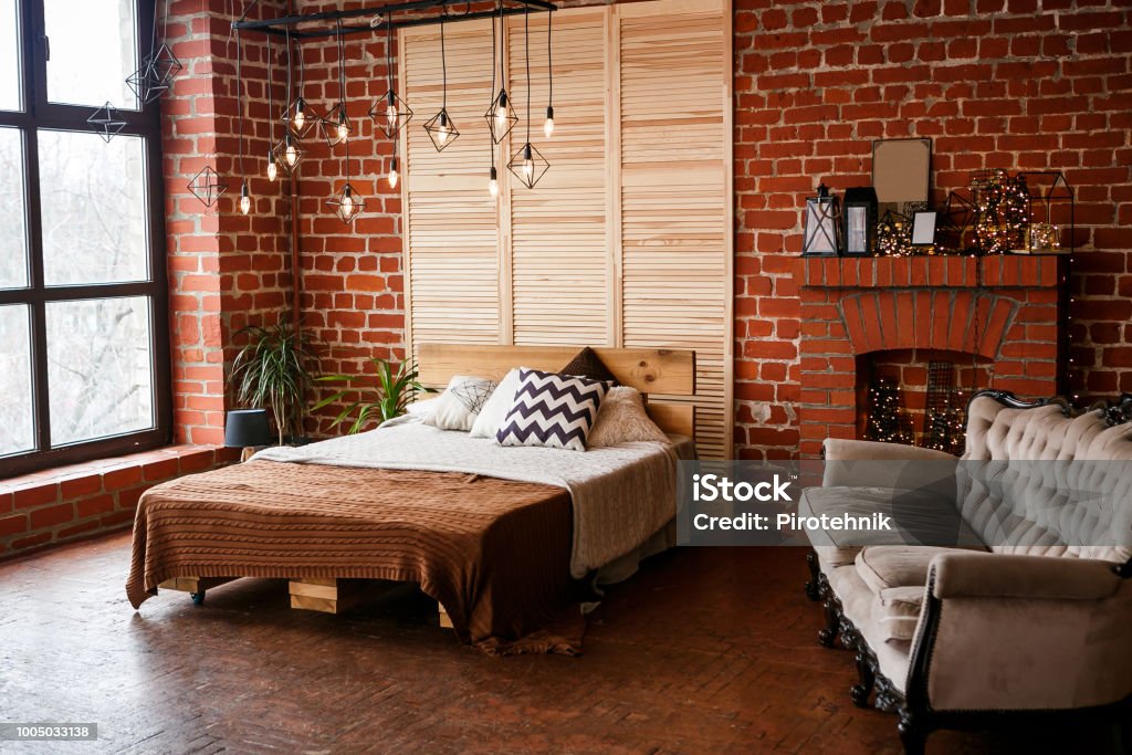 Simple bedroom with double bed, red brick wall and big window Bedroom Stock Photo