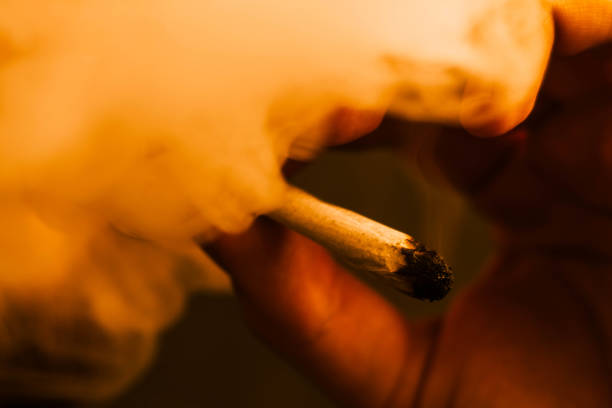 istock Smoke on a black background. A man smokes cannabis weed, a joint Yellow toning 1005039894