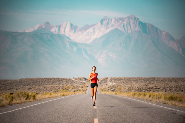 atleta elite donna che corre su una strada nelle montagne sierra, california - maratona foto e immagini stock