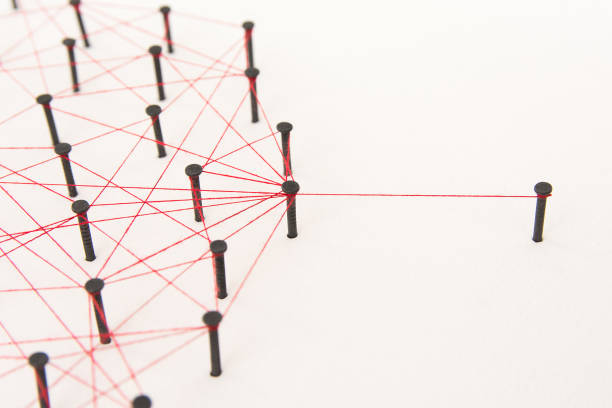 Linking entities, social media, Communications Network, one person connected to the rest networks. Network simulation on white paper linked together created by black nail and red thread with copy space