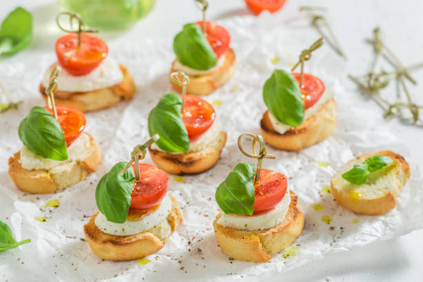 crostini con mozzarella y tomate sobre papel blanco - bruschetta cutting board italy olive oil fotografías e imágenes de stock