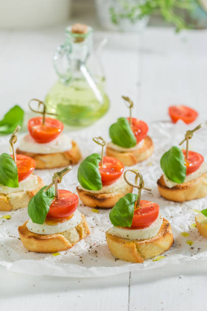 homemade crostini with tomato, mozzarella and basil on white paper - bruschetta cutting board italy olive oil imagens e fotografias de stock
