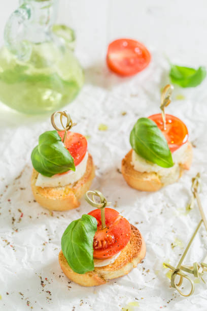 tostadas caseras con tomate y albahaca sobre papel blanco - bruschetta cutting board italy olive oil fotografías e imágenes de stock