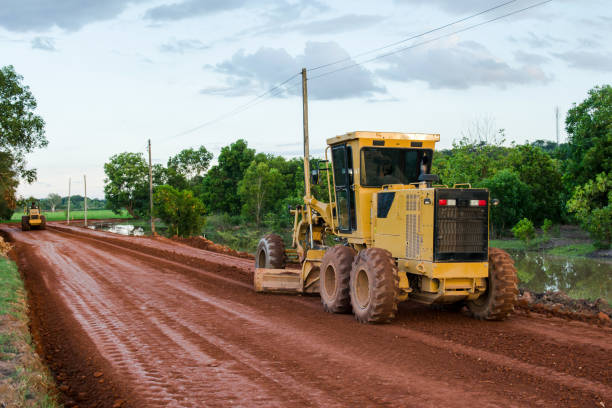 route de niveleuse jaune travaillant sur le chantier de construction de route de la nouvelle route. - grading photos et images de collection
