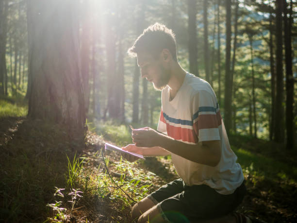 istock portrait of young man brainstorm in the forest with paper notebook taking notes education concept 1005076004