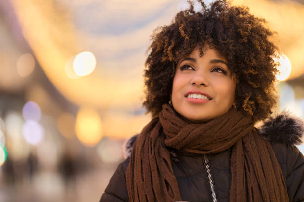 Beautiful young African-American woman looking away Beautiful curly hair millennial African-American woman girl looking away
in the street at night. Blurred background kids winter fashion stock pictures, royalty-free photos & images