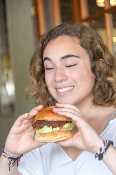 Smiling young woman having a hamburger